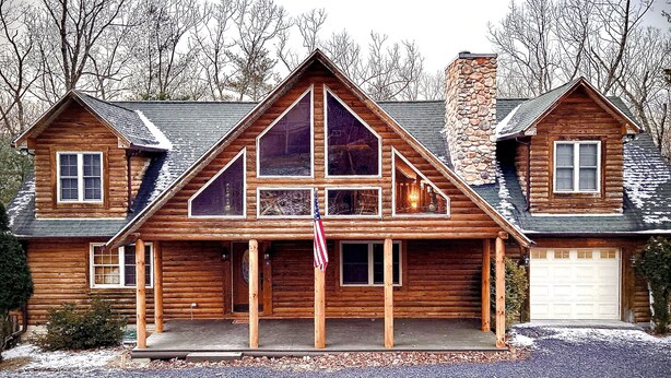 A log cabin with a stone chimney, a garage, and a front porch. - Paradise In Bryce Log Cabin  (Basye)