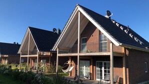 Een tweelaags huis met een schuine kap, een balkon en een hangmat.