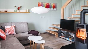 Een moderne woonkamer met een bank, een televisie, een open haard en een trap.