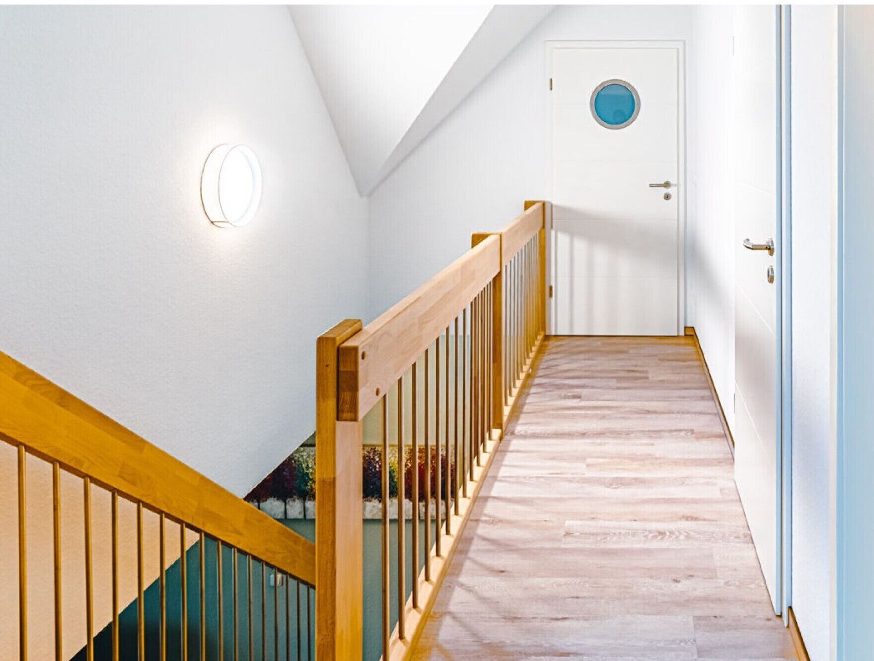 Una scala con ringhiere in legno che conduce a una porta con una finestra circolare.
