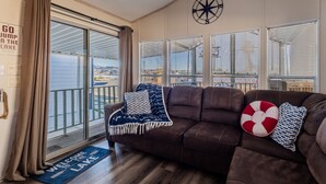 A living room with a brown leather sofa, a welcome mat, and a compass wall decoration. - Island Getaway• Patio View• Boat Ramp & Slips • Pets (Lake Havasu City)