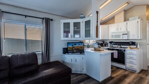 A compact kitchen with white cabinets, a central island, a built-in oven, and a flat-screen TV. - Island Getaway• Patio View• Boat Ramp & Slips • Pets (Lake Havasu City)