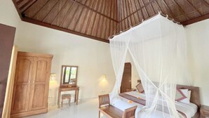 Ein Schlafzimmer mit Himmelbett, Holzmöbeln und einer Decke mit Holzbalken.