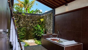 Ein Badezimmer mit Steinwand, Badewanne und Toilette.