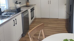 Eine moderne Küche mit weißen Schränken, einem Geschirrspüler, einem Backofen und einer Wanduhr.