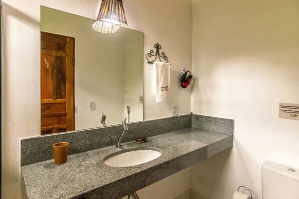 A bathroom with a granite countertop sink, a mirror, a towel rack, and a toilet.