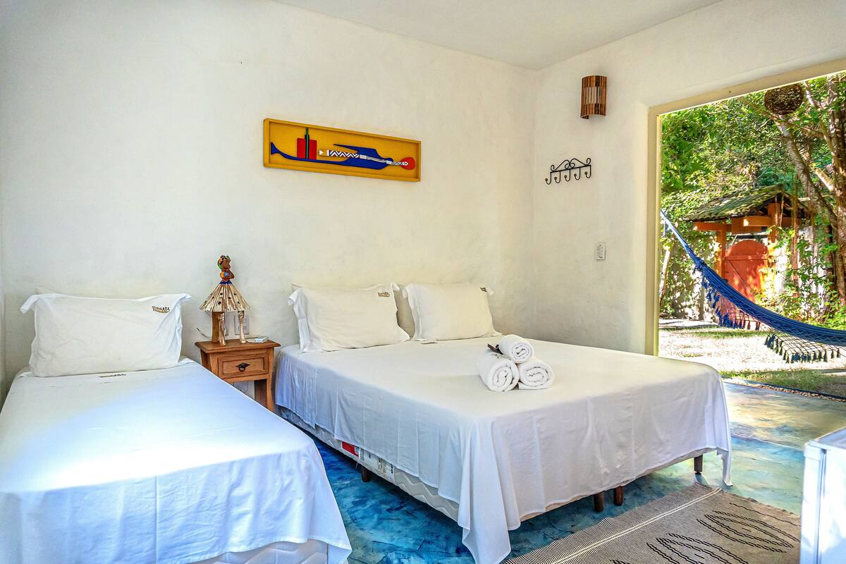 Quarto de hotel com duas camas, uma rede do lado de fora e um quadro com vista para a cidade.