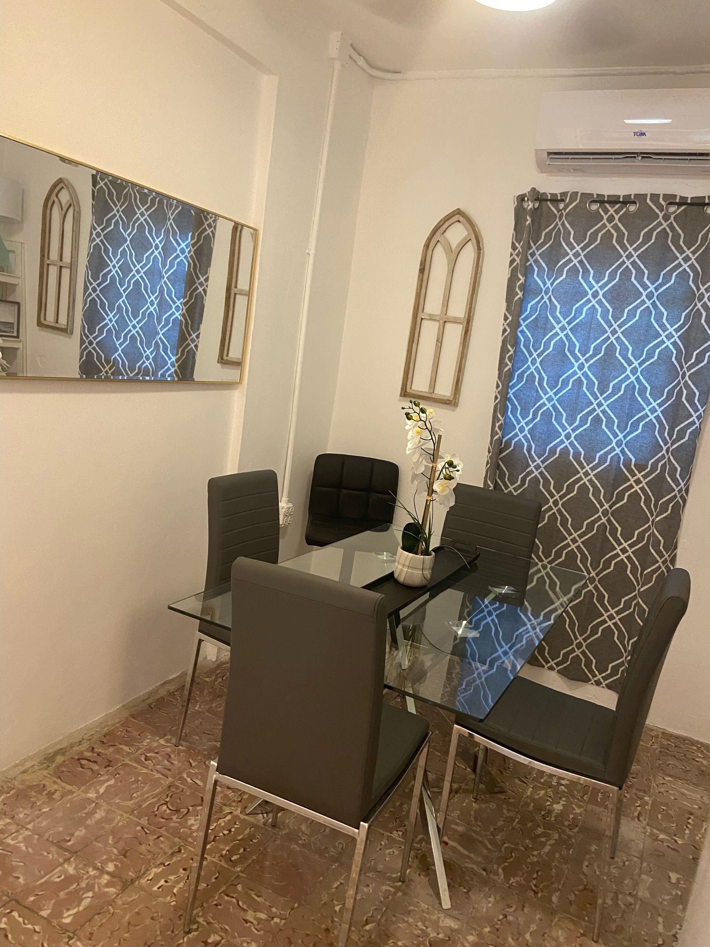 Un comedor moderno con una mesa de vidrio, cuatro sillas y una planta decorativa.