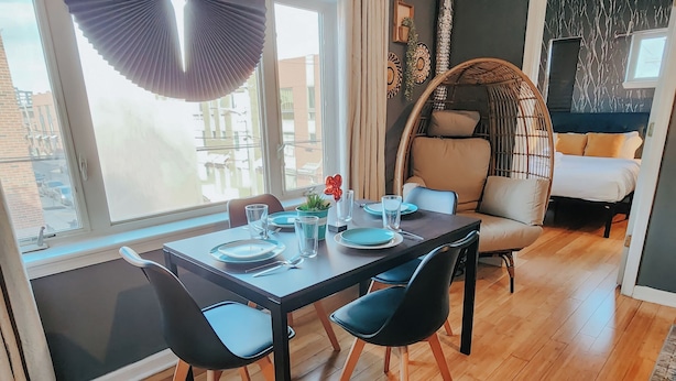 En matplats med ett bord dukat för fyra personer, omgiven av stolar, en fåtölj i rotting och en soffa.