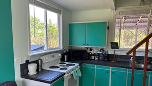 A kitchen with teal cabinets, a white stove, and a window with blinds. - Entire Place & King Sized Bed (Mountain View)