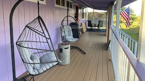 A covered porch with two hanging chairs, a trash can, and a table with chairs. - Entire Place & King Sized Bed (Mountain View)