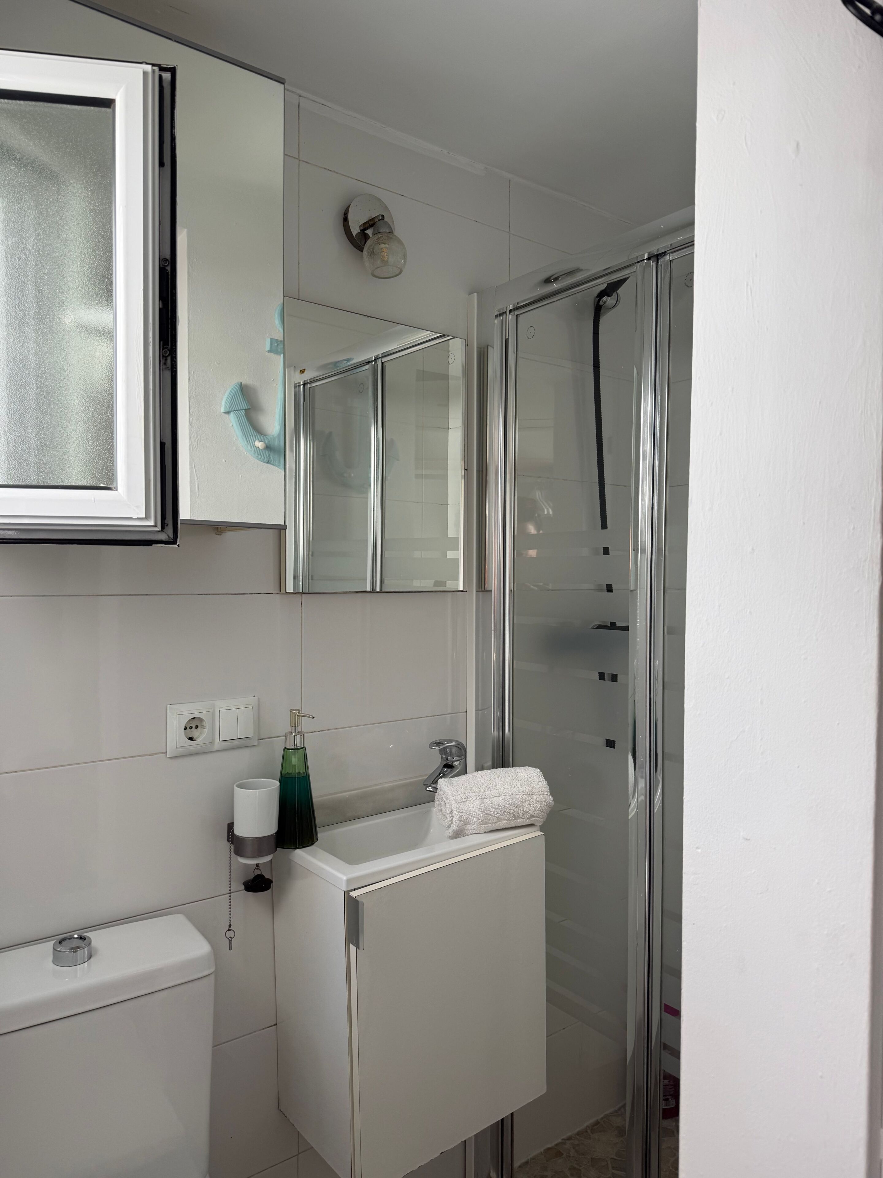 Et badeværelse med toilet, håndvask og brusebad.