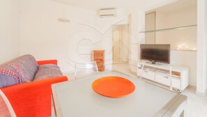 A modern living room with a sofa, a coffee table, a TV, and a glass cabinet. - Modern Casa Lula with double bathroom, garden and terrace immersed in the greenery of Marina di Camp (Campo nell'Elba)