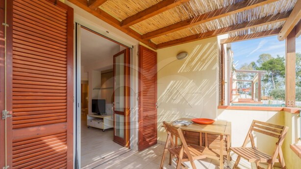 An open wooden door leading to a room with a television and a small table with chairs. - Modern Casa Lula with double bathroom, garden and terrace immersed in the greenery of Marina di Camp (Campo nell'Elba)