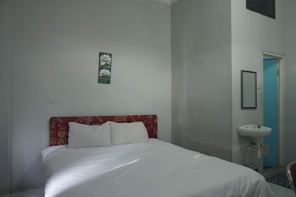 Une chambre à coucher avec un lit, un tableau accroché au mur et un lavabo.