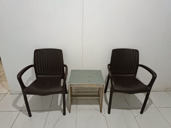 Dos sillas de mimbre negro con una pequeña mesa de madera en el centro.