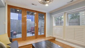 A room with a sliding glass door leading to a backyard, a wooden bench, and a window with blinds. - Walk to Main St, City Dock, USNA from Historic Catch 22 w Private Patio (Annapolis)