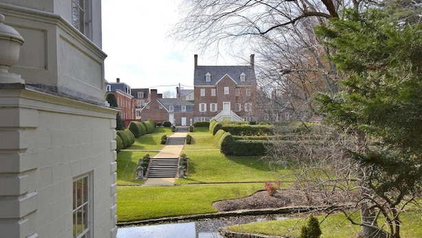 A well-maintained garden with a pond, neatly trimmed hedges, and a brick building in the background. - Walk to Main St, City Dock, USNA from Historic Catch 22 w Private Patio (Annapolis)