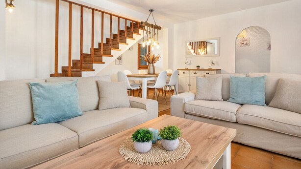 Una sala de estar moderna con una escalera, dos sofás, una mesa de centro y un comedor.
