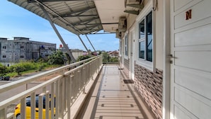 A covered balcony with a metal roof, a white door with a 'N' sign, and a view of a building in the background. - Hotel O Putri Homestay Syariah Near SPBU 14.282.694 (Air Hitam) (Pekanbaru)