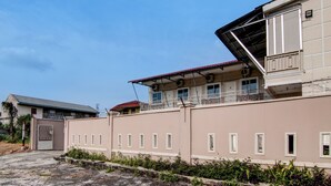 A multi-story building with a gated entrance, a balcony on the upper floor, and a red roof. - Hotel O Putri Homestay Syariah Near SPBU 14.282.694 (Air Hitam) (Pekanbaru)