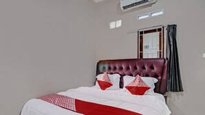A neatly made bed with a red and white bedspread, a tufted headboard, and two pillows with red and white patterns. - Hotel O Putri Homestay Syariah Near SPBU 14.282.694 (Air Hitam) (Pekanbaru)