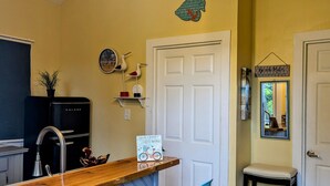 Una cocina compacta con una barra de madera, dos sillas azules, un refrigerador y una puerta con un cartel.