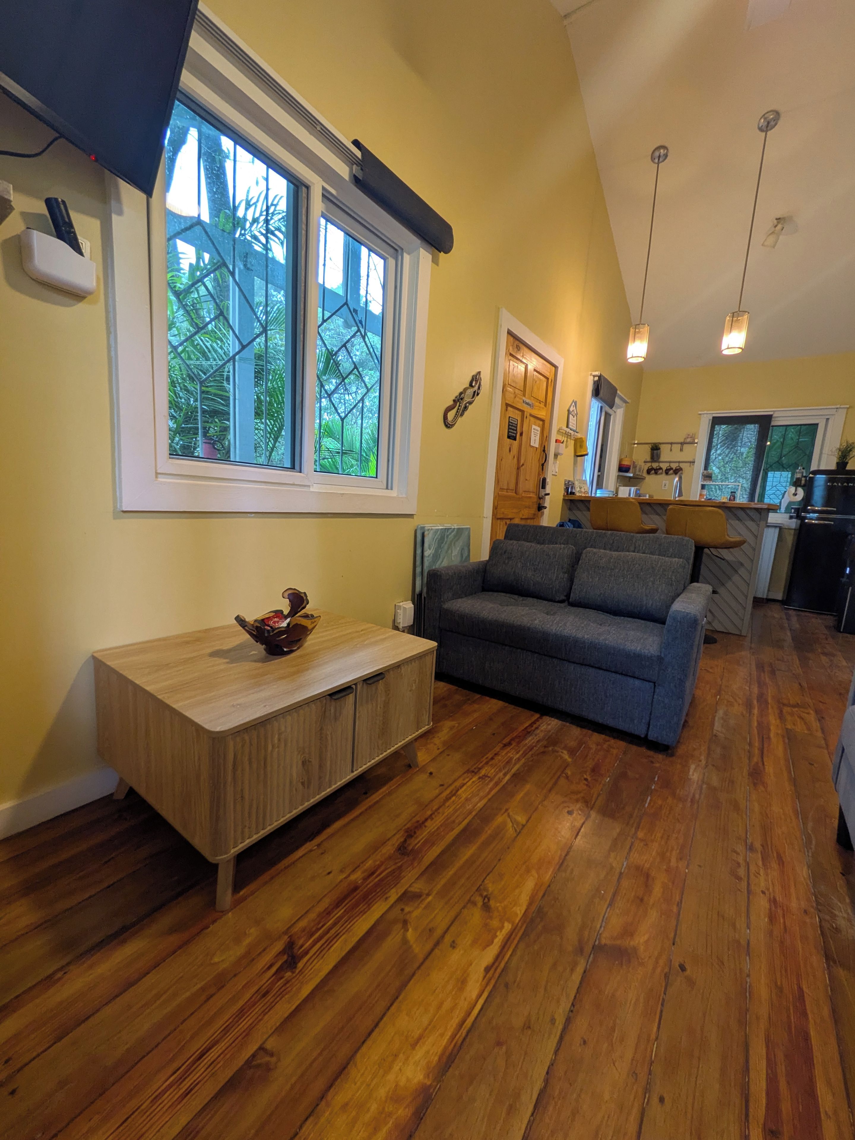 A modern living room with a wooden floor, a grey sofa, and a wooden coffee table.