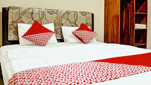 Een keurig opgemaakt bed met een beddekleed met een patroon en twee kussens met een rood-wit ontwerp.