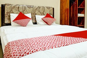 A neatly made bed with a patterned bedspread and two pillows with a red and white design. - Hotel O Homestay Juwita Perdana Syariah (Belitang)