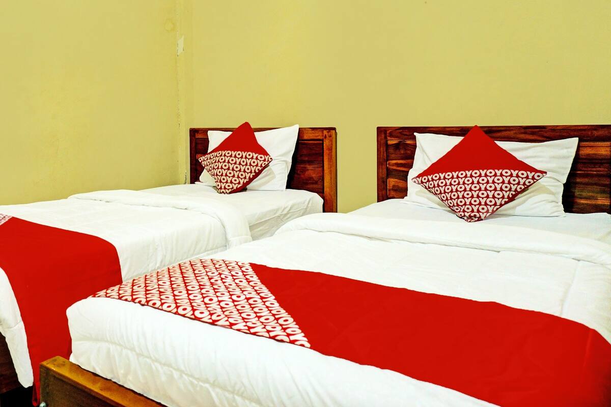 Two twin beds with red and white bedding, wooden headboards, and a red throw blanket.