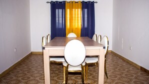 A dining room with a wooden table and white chairs with gold accents. - Richard  (Yaoundé)
