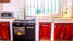 A kitchen with a stove, microwave, and cabinets. - Richard  (Yaoundé)