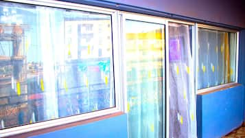 A room with large windows, a blue wall, and a visible cityscape outside.