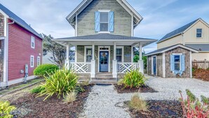 A two-story house with a front porch, a small attached garage, and a gravel driveway. - Relax and Refresh, Seconds From Beach, Bedrooms w/ En-Suite Bathrooms, Community Pool, Fire-Pit, BBQ (Lincoln City)