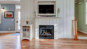 A living room with a fireplace, a mounted TV, and a bookshelf. - Relax and Refresh, Seconds From Beach, Bedrooms w/ En-Suite Bathrooms, Community Pool, Fire-Pit, BBQ (Lincoln City)