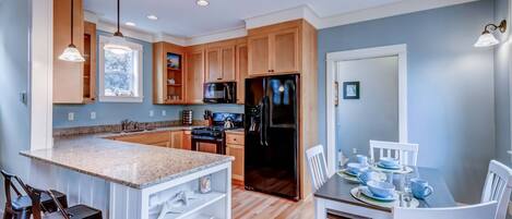 A modern kitchen with granite countertops, wooden cabinets, and stainless steel appliances.