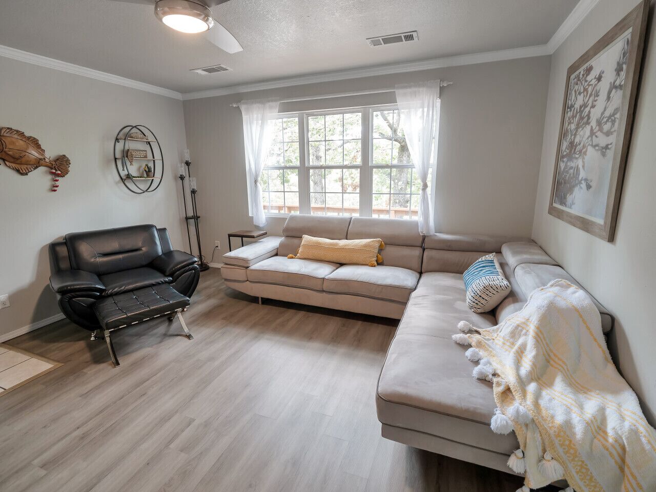 A living room with a sofa, a chair, and a window with curtains.