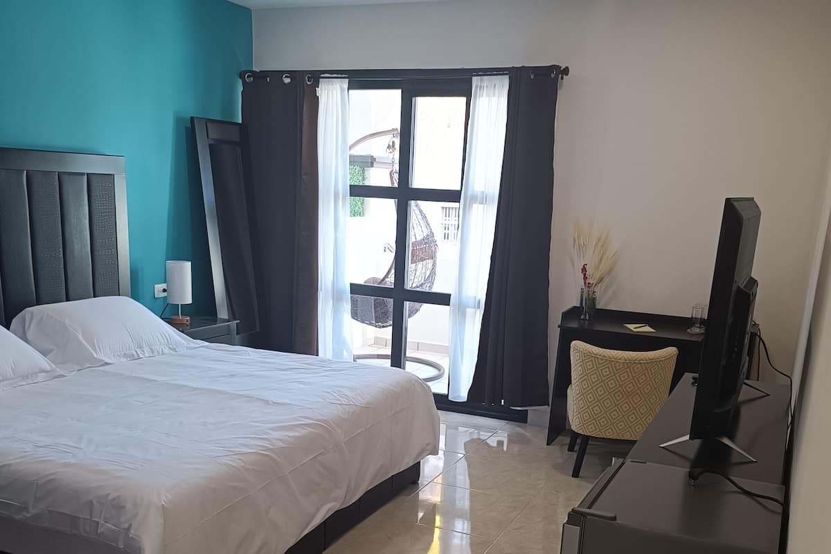 Habitación de hotel con cama, escritorio y televisor, y vista al exterior.