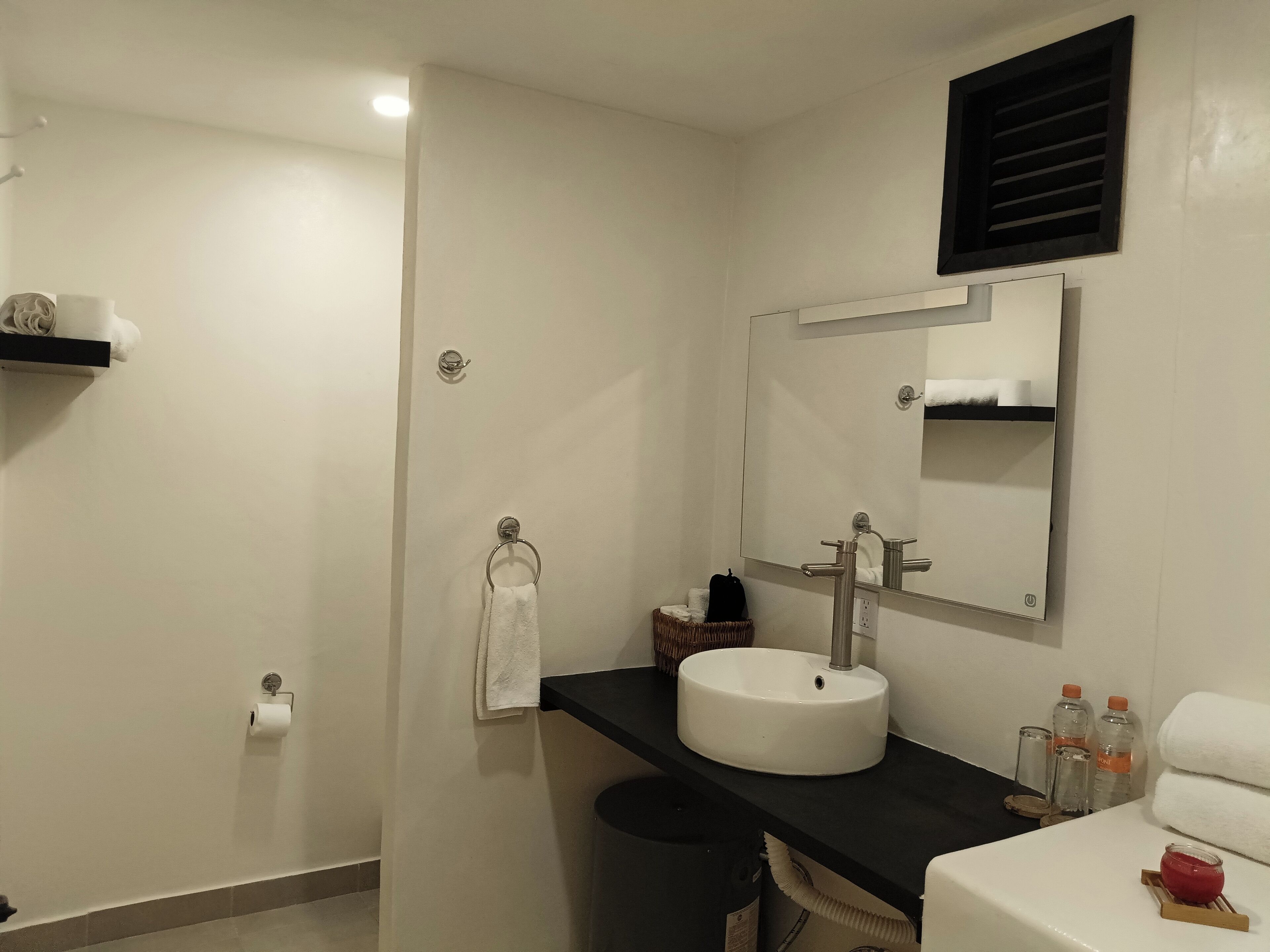 A modern bathroom with a white sink, a large mirror, and a black countertop.