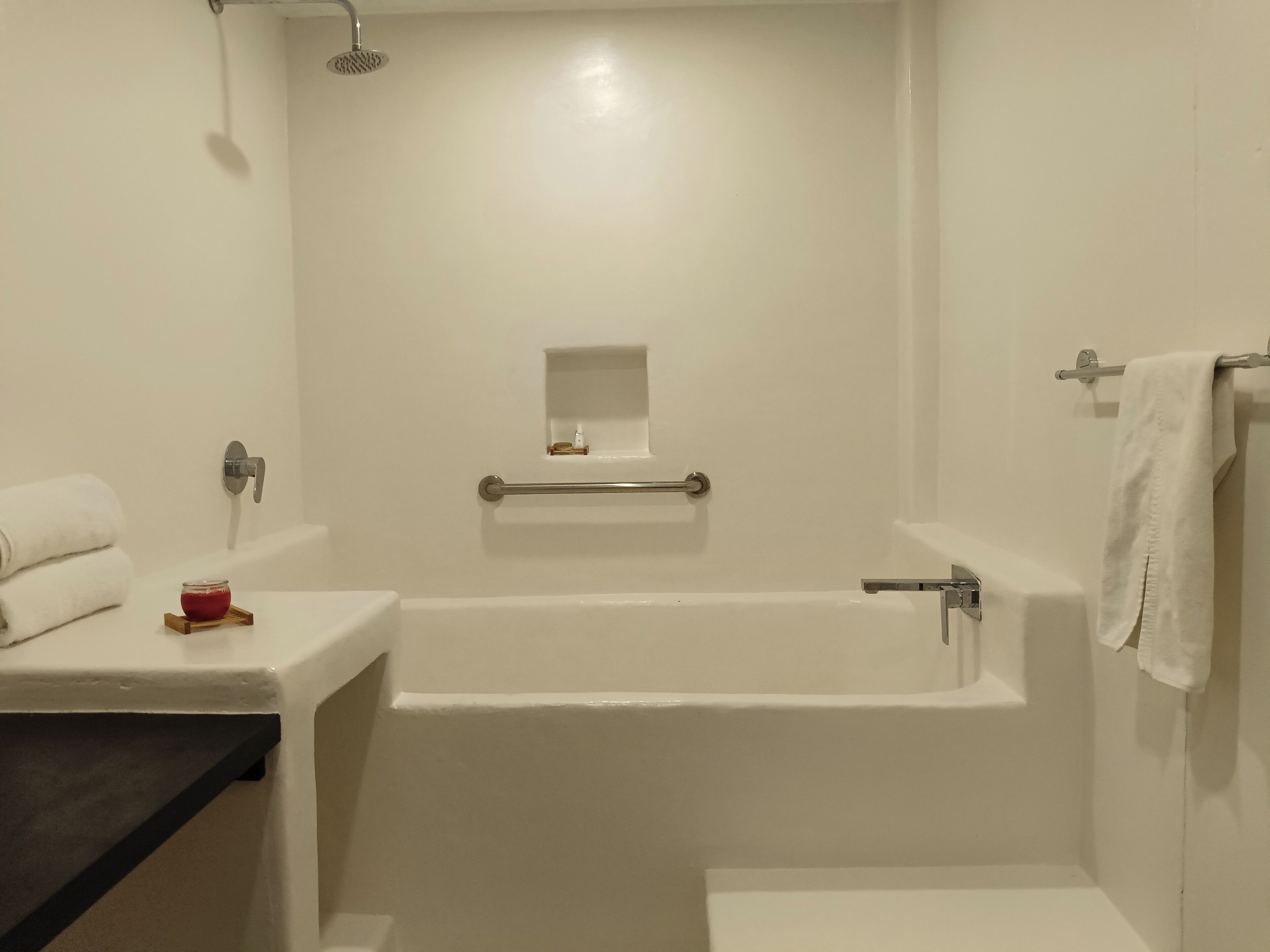 Un baño con bañera, inodoro, lavabo, toallero y cabezal de ducha.