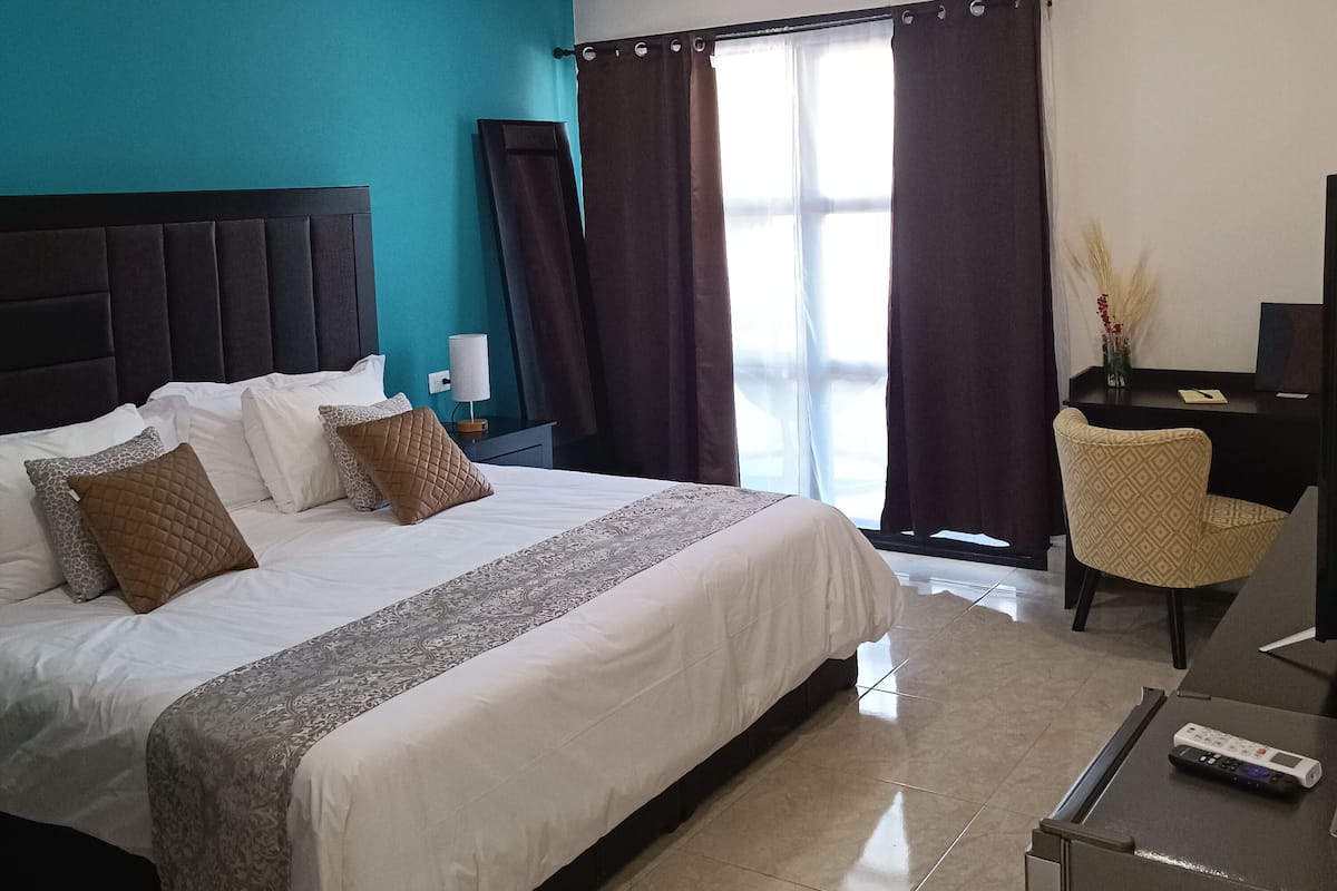 Una habitación de hotel con una cama grande, un escritorio, una silla y un televisor.