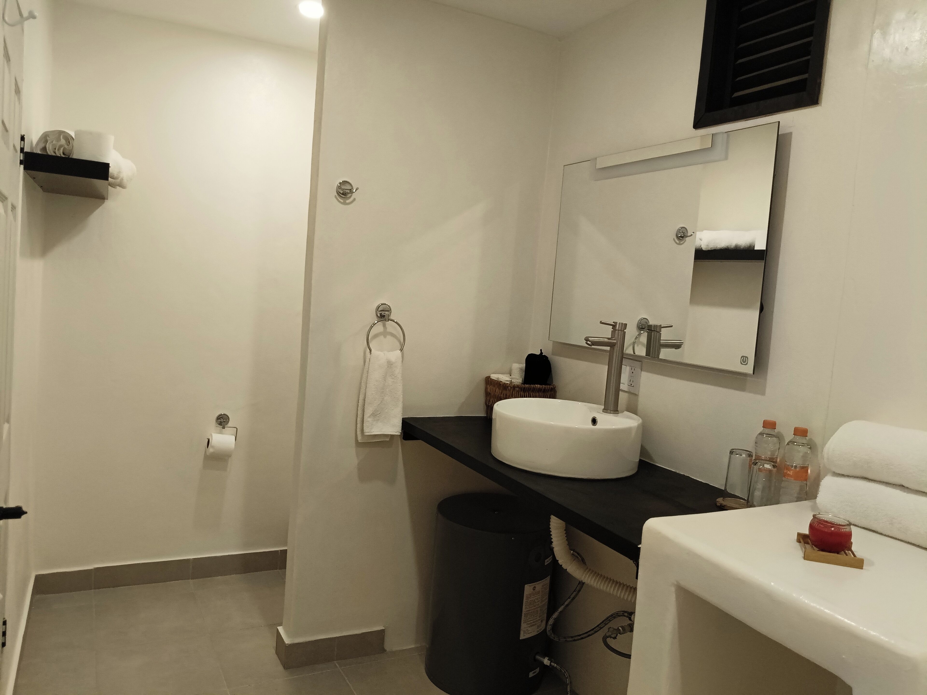 A bathroom with a white sink, a mirror, a towel rack, and a trash bin.