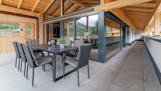 Un intérieur moderne en bois, avec un coin repas comprenant une table et des chaises, une plante en pot et une bouteille de vin.