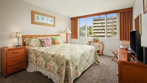 A hotel room with a bed, a desk, a television, and a window with curtains.