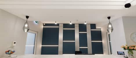 A modern reception desk with a marble top, overhead lighting, and a digital clock displaying the time.