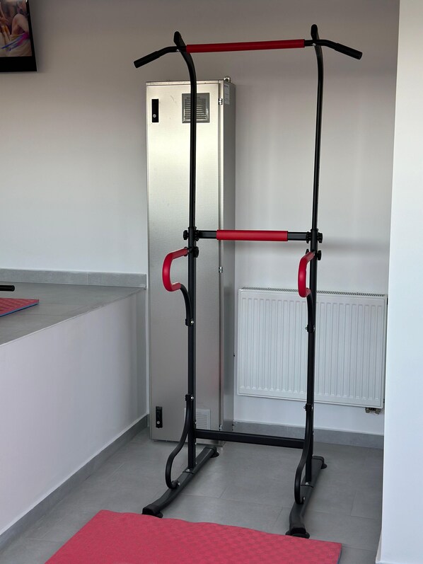 A compact room with a pull-up bar structure against a wall, a radiator, and a door.