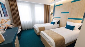 A hotel room with two beds, a desk, and a chair.