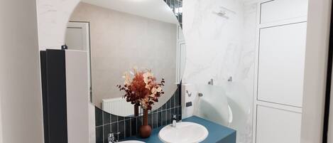 Un baño moderno con dos lavamanos, un espejo grande y un florero con flores.