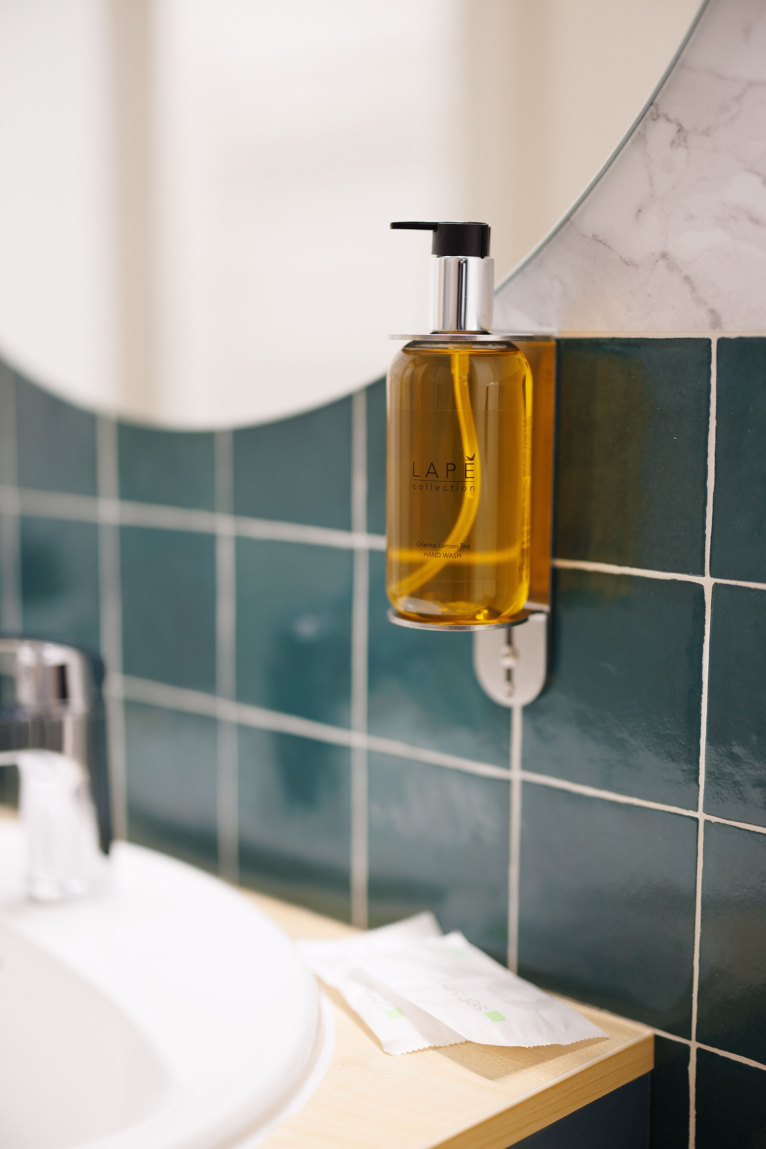 A bathroom with a hand soap dispenser mounted on a tiled wall.